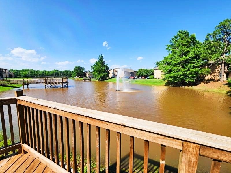 A wooden deck overlooks a flooded area with a bridge and buildings in the distance.