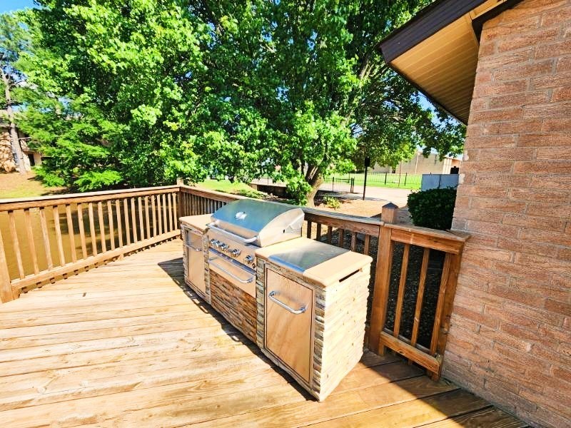 A wooden deck with a grill and a cooler on it.