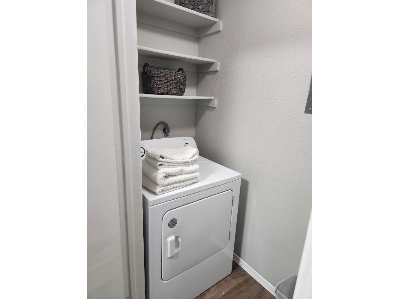 A white laundry machine is in a cabinet with towels on top.