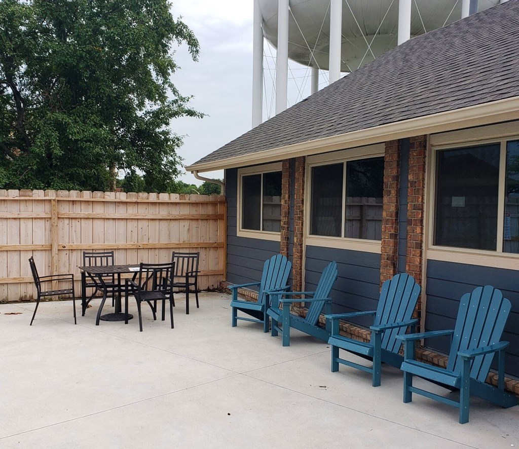 A patio with blue chairs and a table.