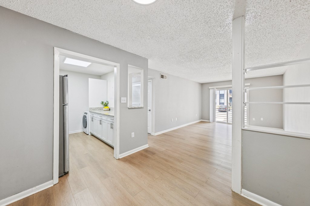 A kitchen with white appliances and wooden floors.