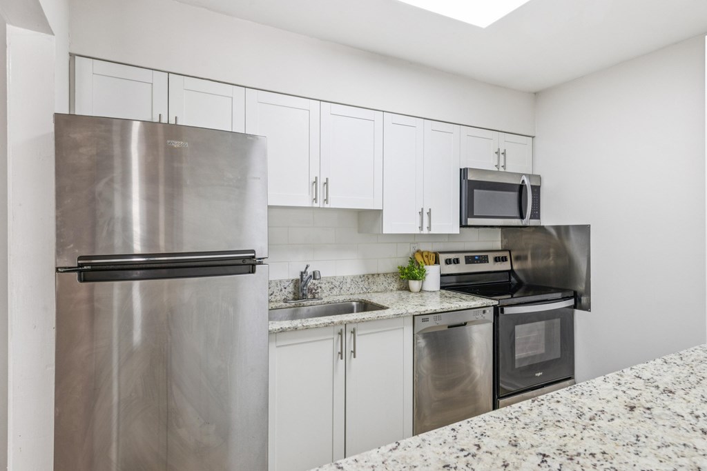 A kitchen with a stainless steel refrigerator, microwave, oven, and sink.