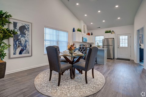 A dining room with a table set for two and a plant on the side table.