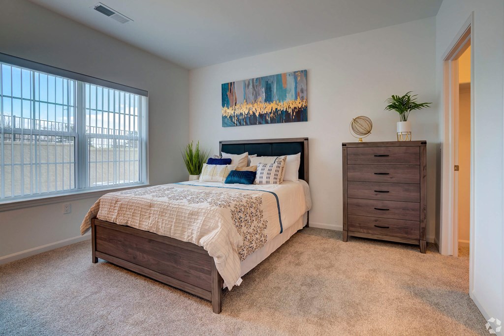 A bedroom with a bed, nightstand, and a painting on the wall.