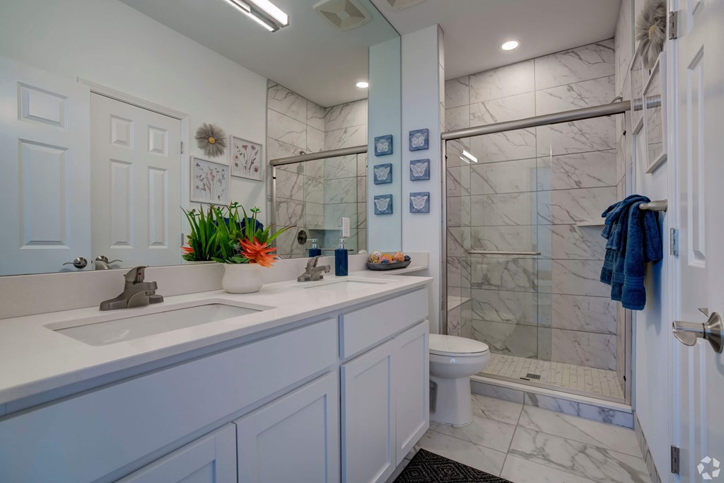 A white bathroom with a sink, toilet, and shower.
