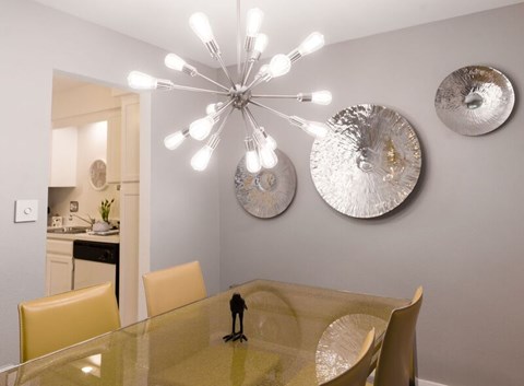 A dining room with a glass table and chairs and a chandelier.
