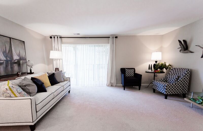A living room with a white couch and a painting on the wall.