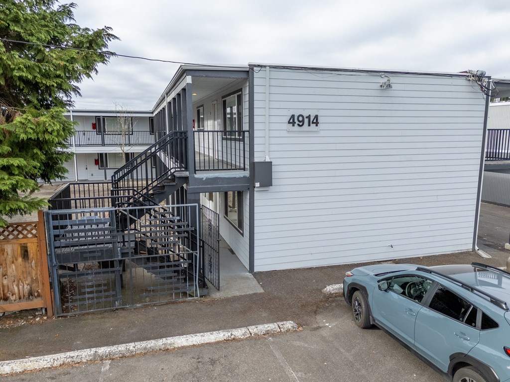 A car is parked in front of a building with the number 4914 on it.