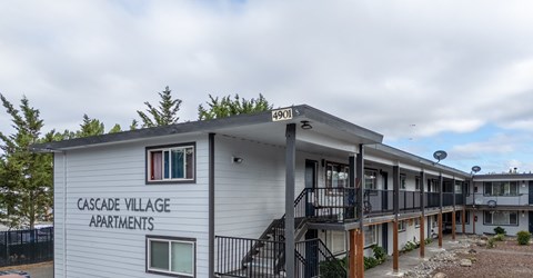 Cascade Village Apartments is a white building with a black railing.