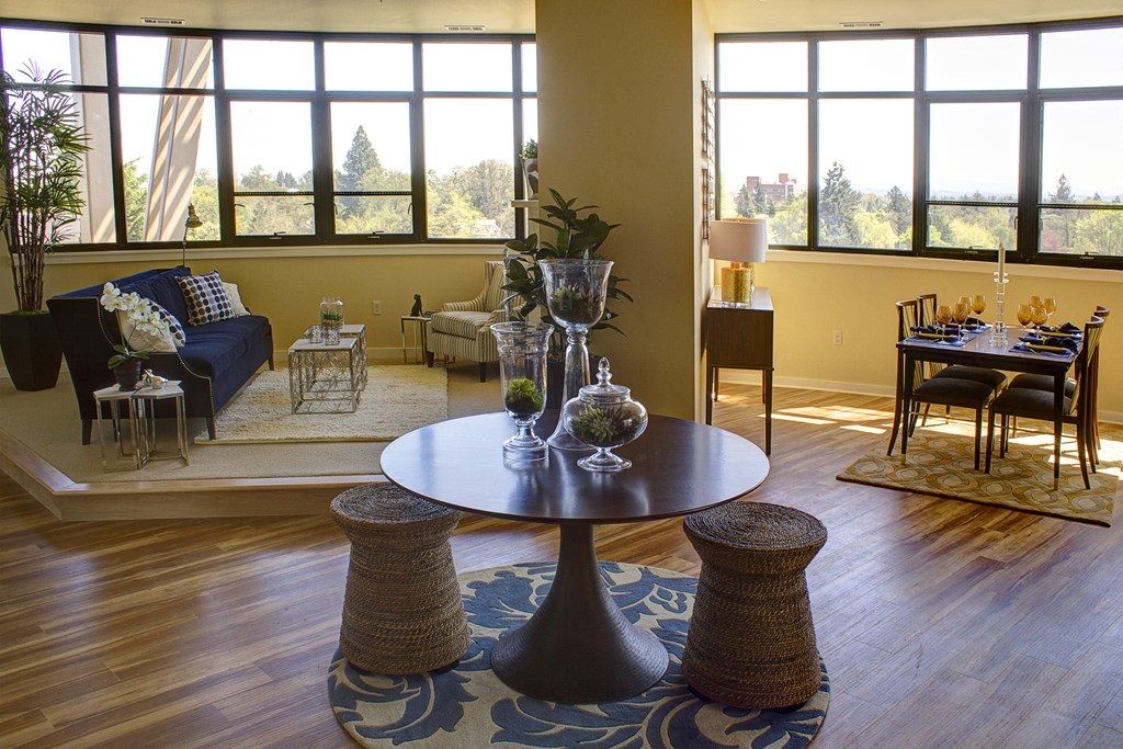 a living room with a table and chairs and large windows