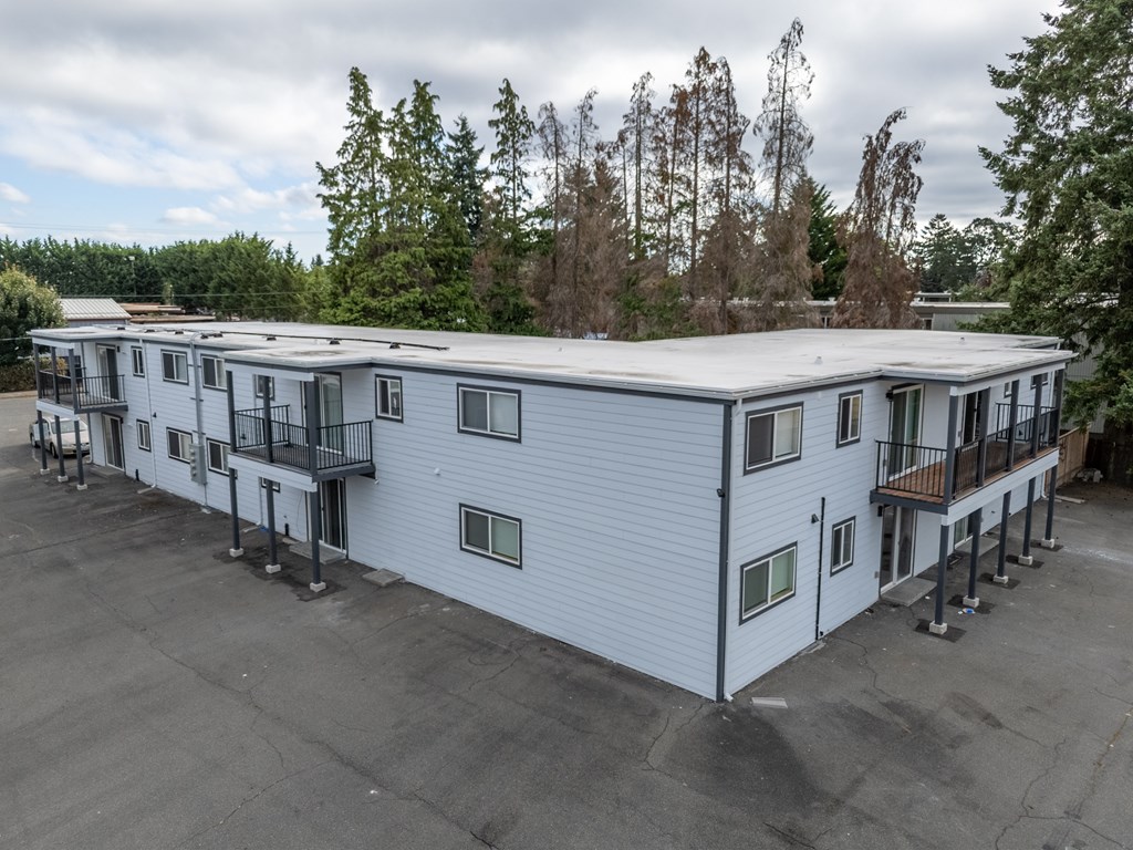 A large white building with a grey roof and a balcony on the second floor.