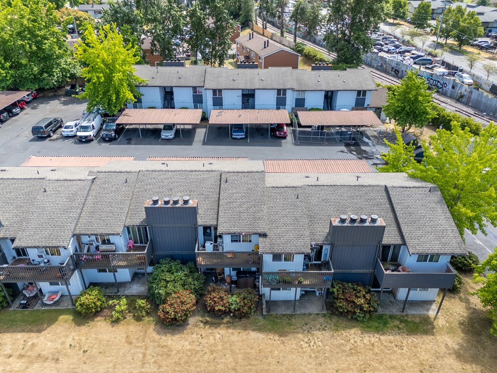 A parking lot is in front of a building with a grey roof.