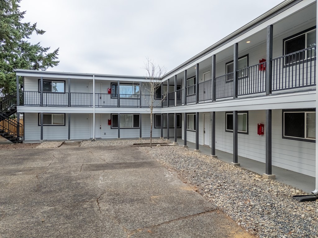 A parking lot in front of a white building with a black railing.
