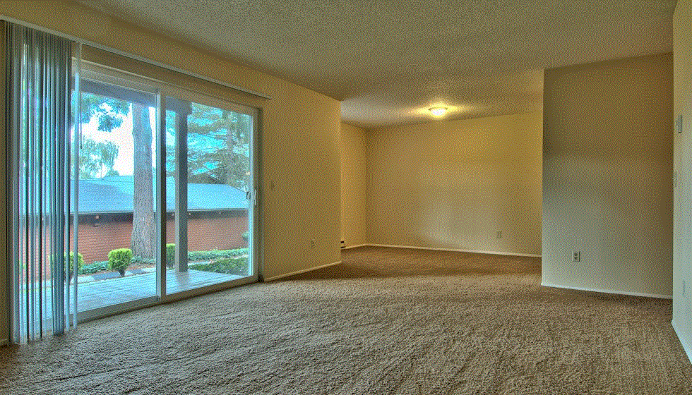 an empty living room with sliding glass doors to a patio