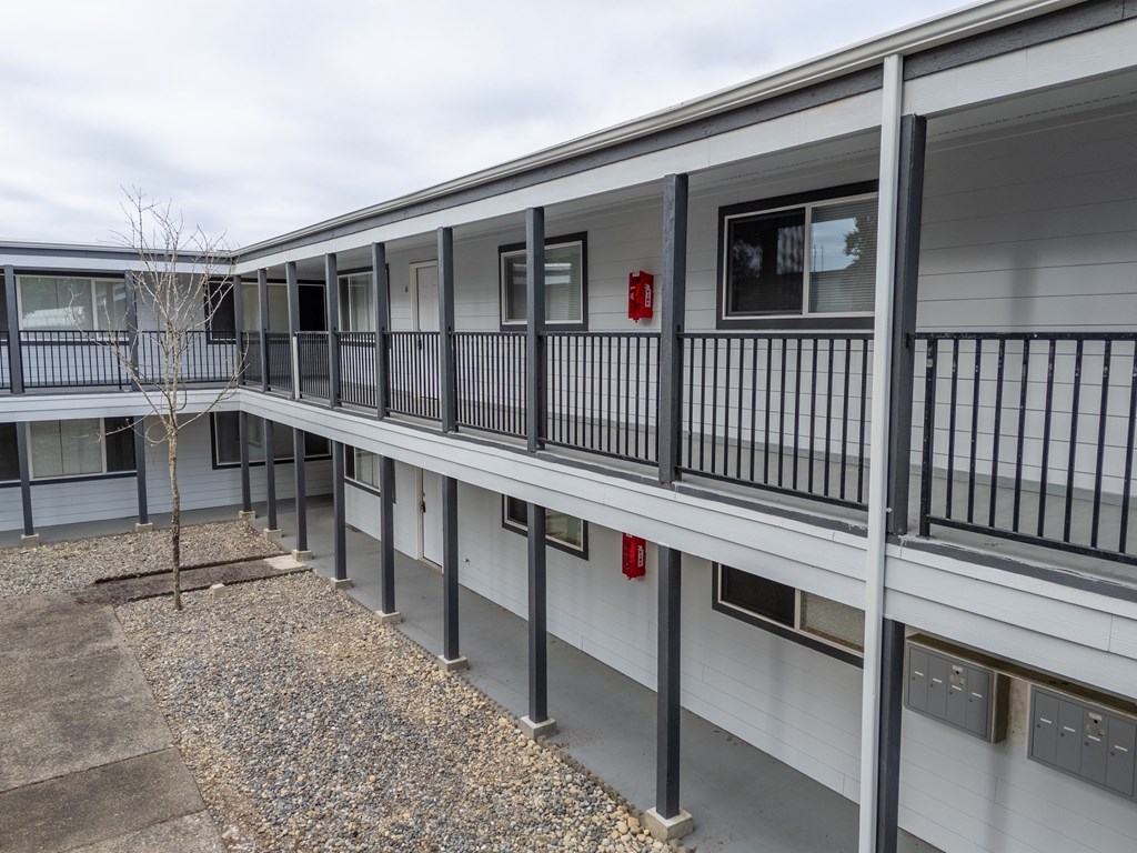A building with a balcony and a tree in front of it.