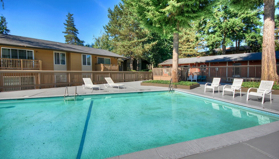 a swimming pool with chairs and a building in the background