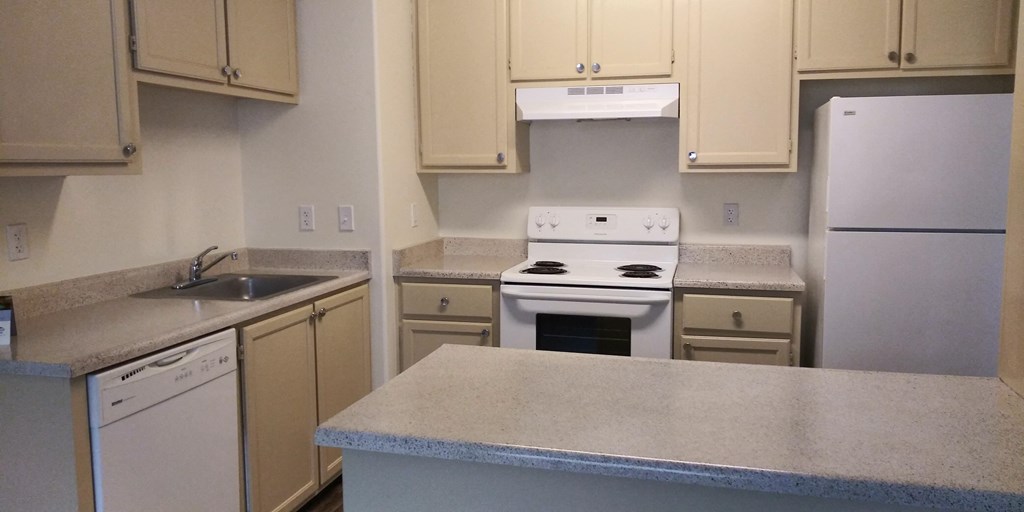 an empty kitchen with white appliances and white cabinets