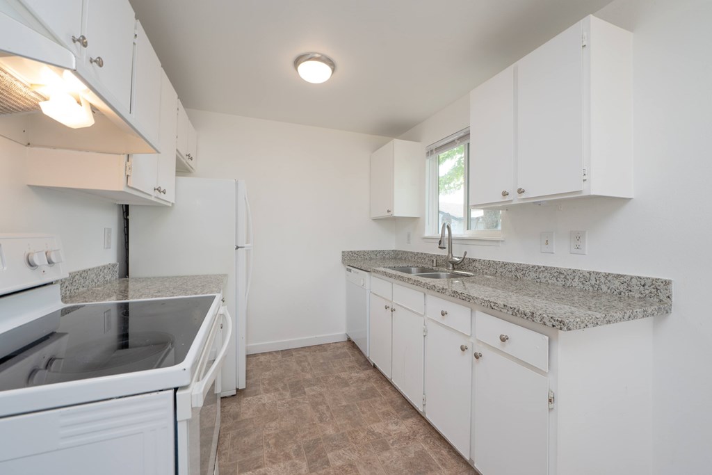 A kitchen with white cabinets and granite countertops.