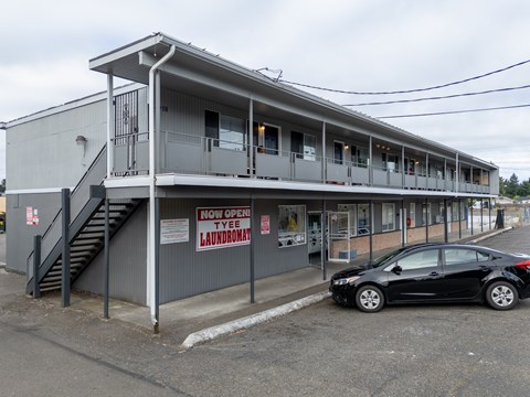 A car is parked in front of a laundromat.