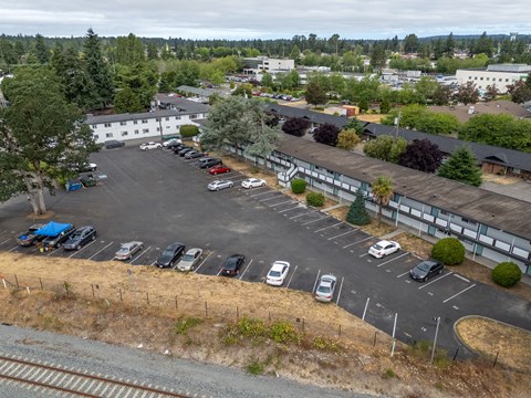 A parking lot with cars and a train track in the foreground.