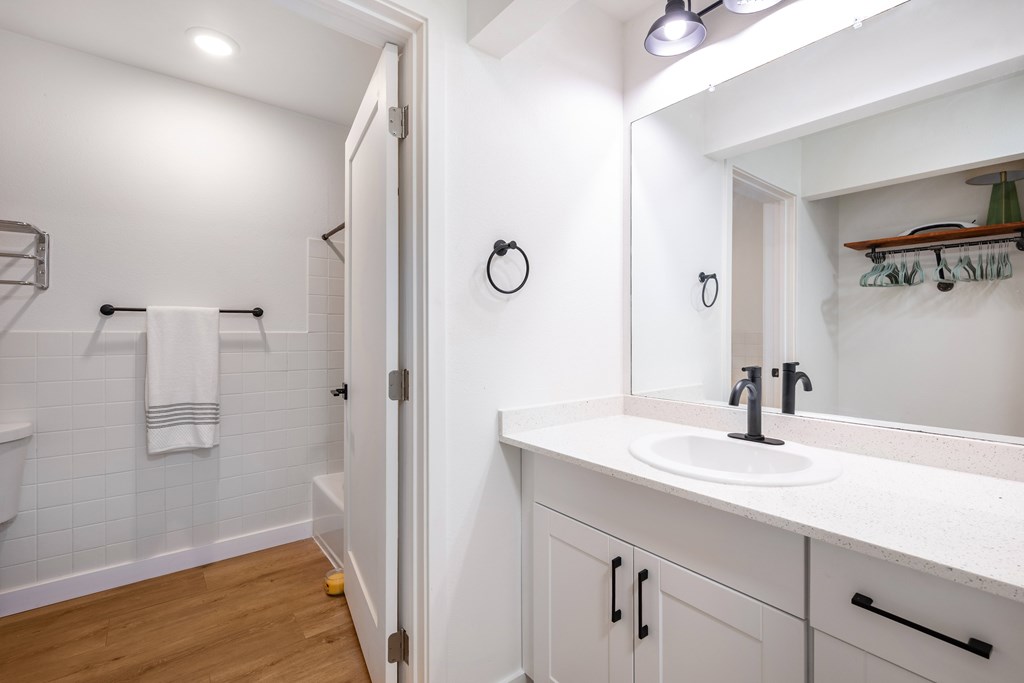 A white bathroom with a white sink and a white towel hanging on the wall.