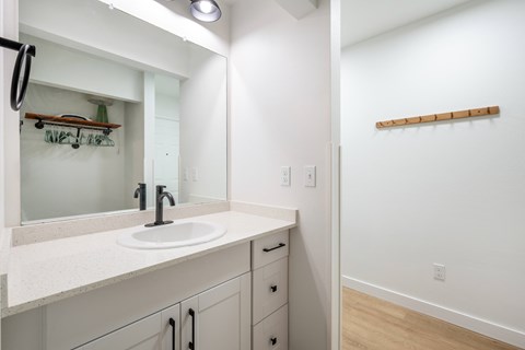 A bathroom with a sink, mirror, and wooden shelf.