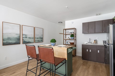 A kitchen with a table and chairs and a refrigerator.