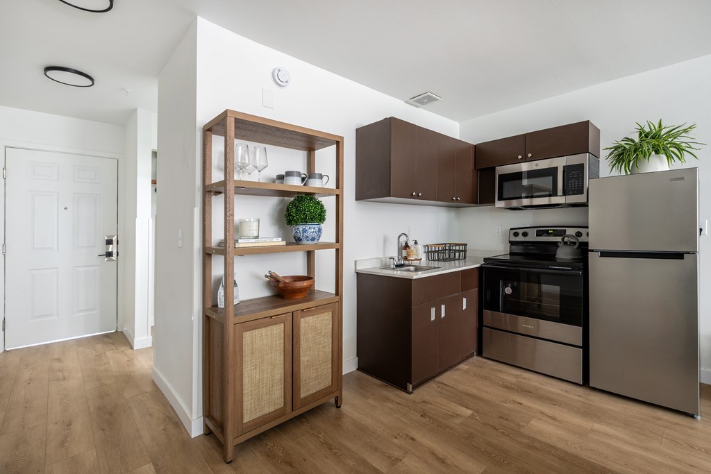 A modern kitchen with wooden floors and stainless steel appliances.