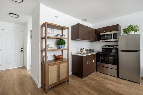 A modern kitchen with wooden floors and stainless steel appliances.