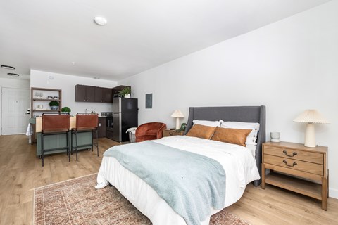 A bedroom with a bed, nightstand, and chair.