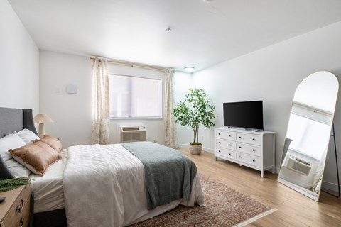 A bedroom with a bed, dresser, and window.