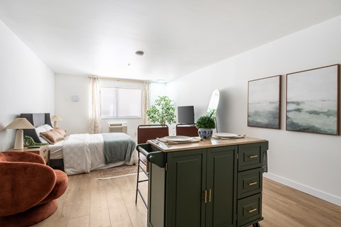 A bedroom with a bed, chair, and cabinet.