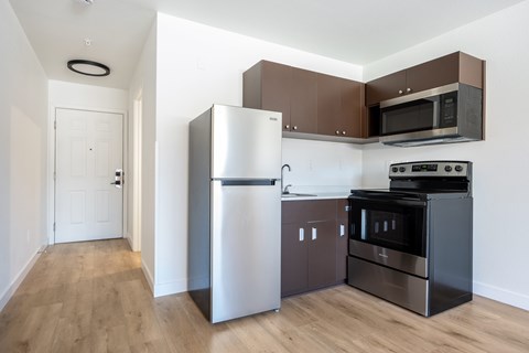 A kitchen with a refrigerator, oven, microwave, and dishwasher.