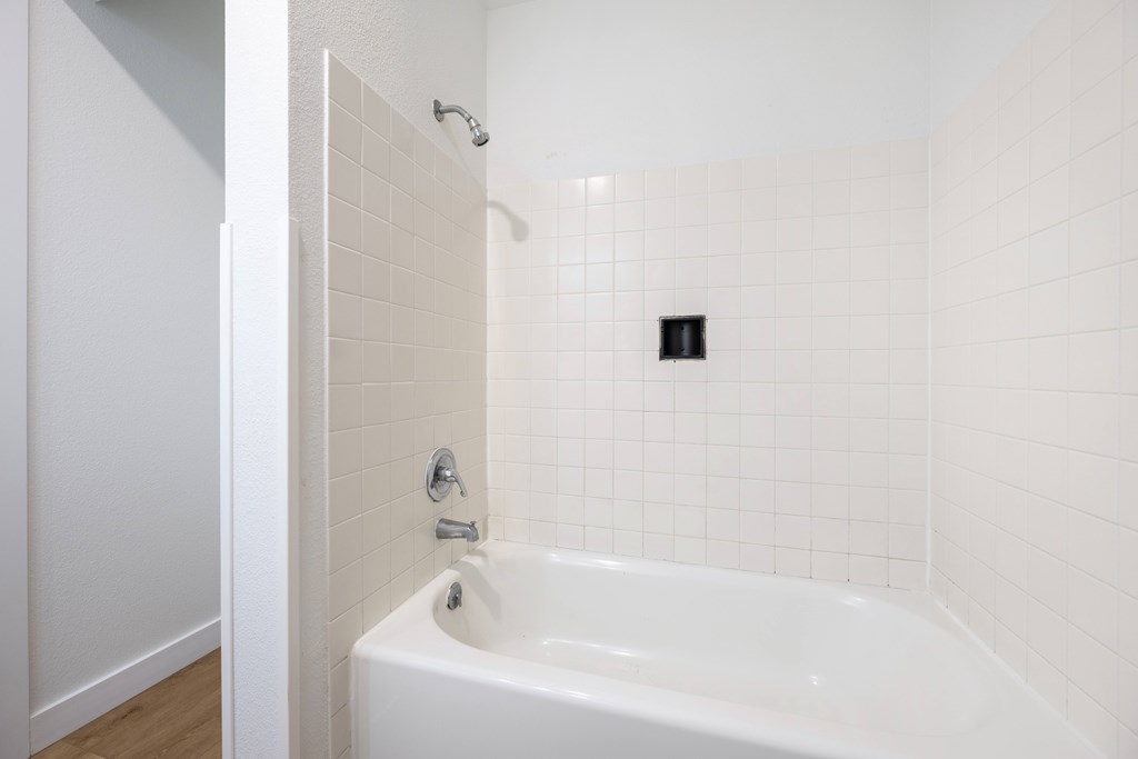 A white bathroom with a white tub and a white shower.