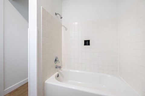 A white bathroom with a white tub and a white shower.