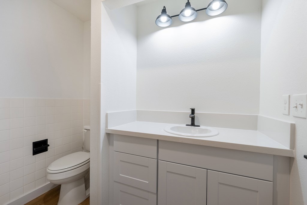 A white bathroom with a toilet, sink, and light fixture.