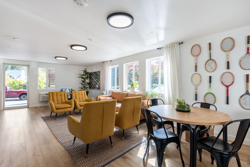 Tennis rackets are hanging on the wall in a room with a table and chairs.