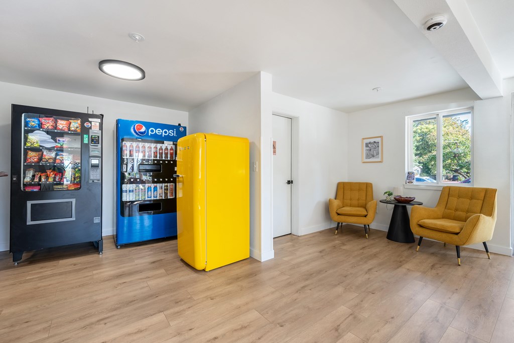 A yellow refrigerator sits in a room with a Pepsi machine in the background.