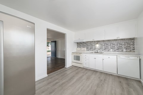 A kitchen with white cabinets and a stone backsplash.