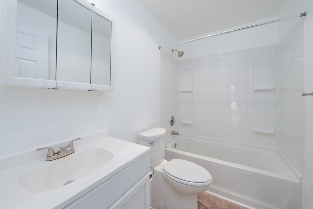 A white bathroom with a toilet, sink, and bathtub.