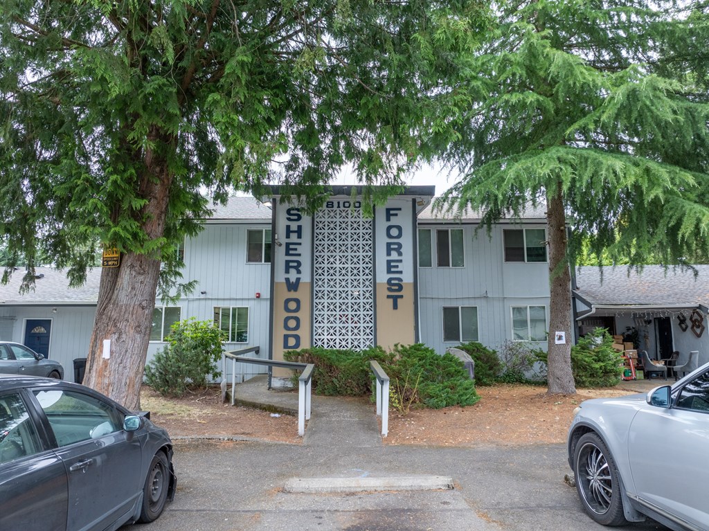 A white building with a sign that says Big Forest Shedwood.