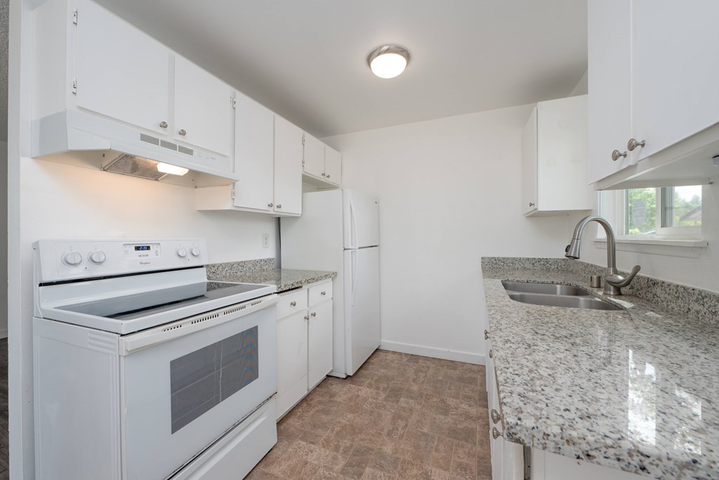 A kitchen with white cabinets and a granite countertop.