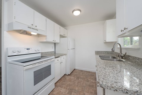 A kitchen with white cabinets and a granite countertop.