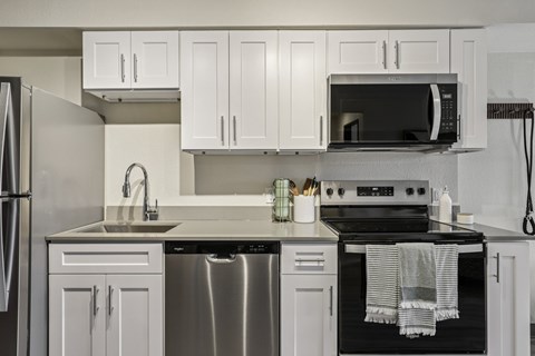 A modern kitchen with white cabinets and stainless steel appliances.
