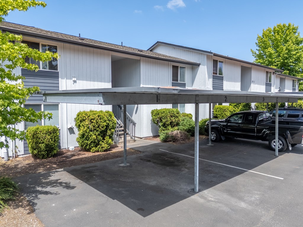 A black truck is parked in a parking lot under a covered area.