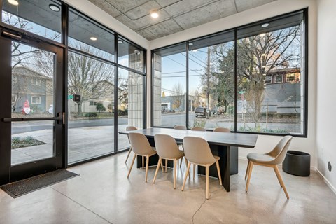 A modern dining room with a table and chairs in front of large windows.