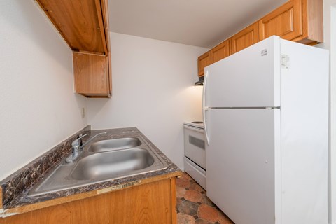 A kitchen with a white fridge and a marble counter top.
