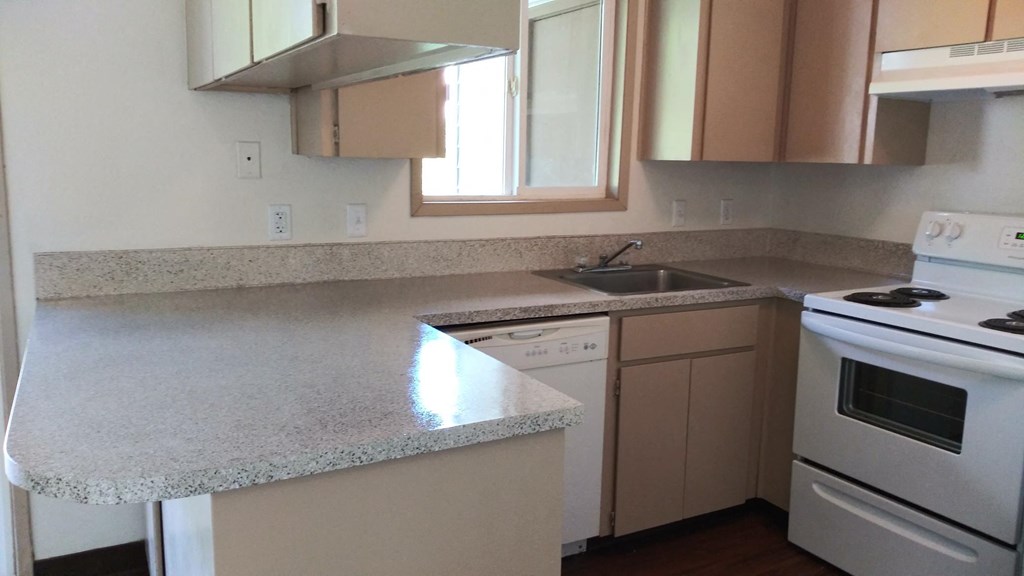 an empty kitchen with white appliances and granite counter tops