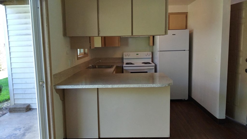 an empty kitchen with white appliances and a counter top