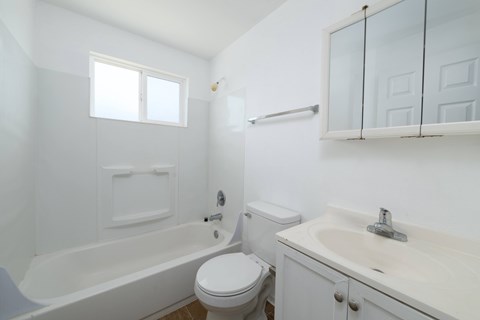 A white bathroom with a toilet, sink, and bathtub.